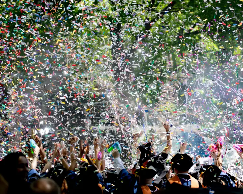 a street with people celebrating and confetti falling