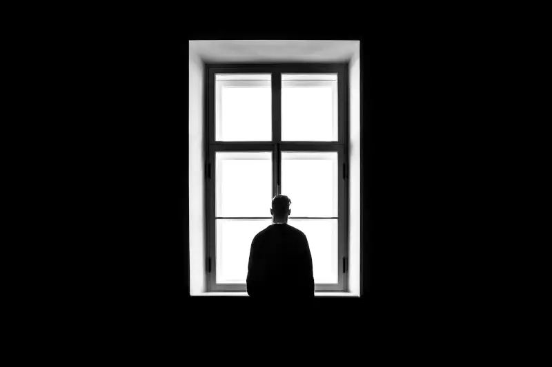 Man standing alone in front of a window